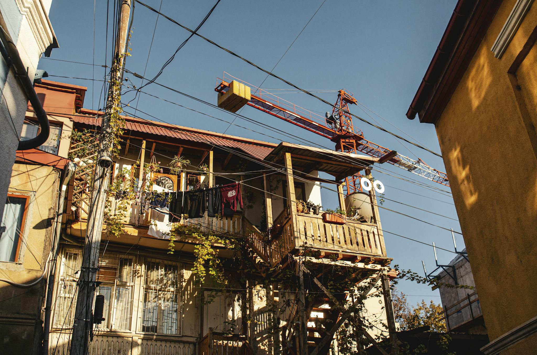 A cityscape with a construction crane beside a wooden balcony.